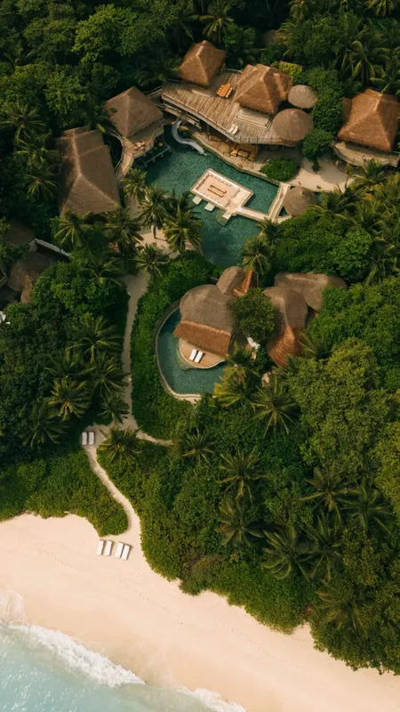 Vue aérienne d'un complexe hôtelier tropical avec piscine et végétation luxuriante