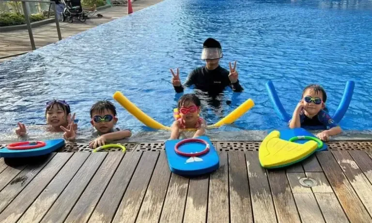 Quatre enfants souriants dans une piscine avec accessoires de flottaison