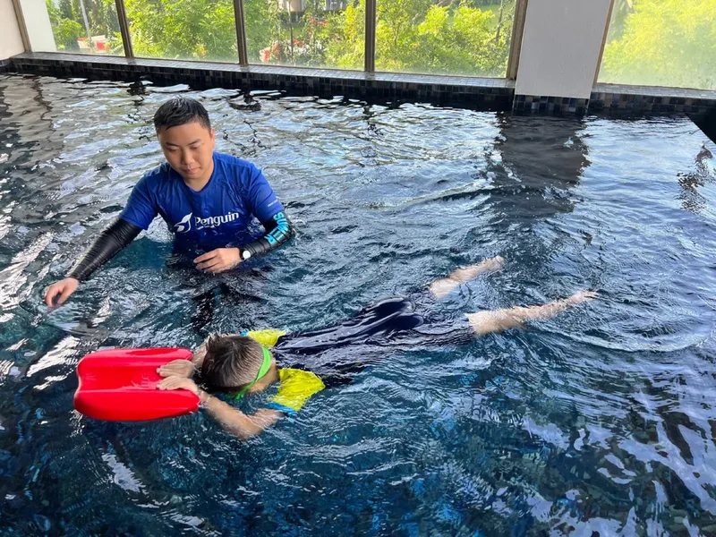 Deux personnes dans une piscine, un instructeur aide un élève