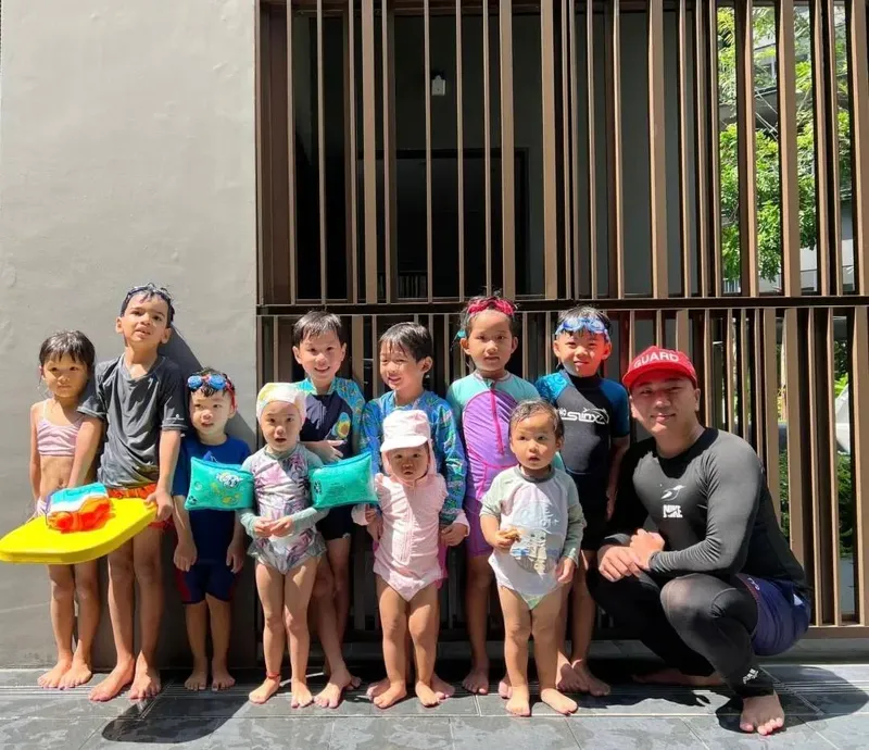 Groupe d'enfants et un moniteur souriants, prêts pour une activité aquatique