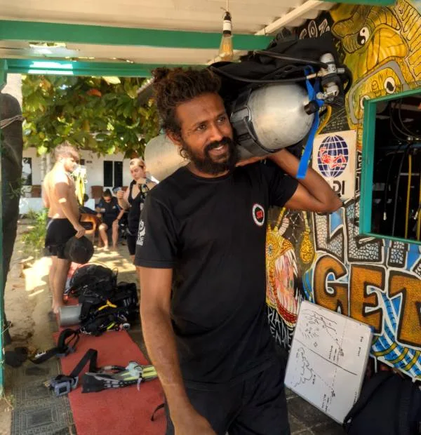 Un homme transporte des bouteilles de plongée devant un centre