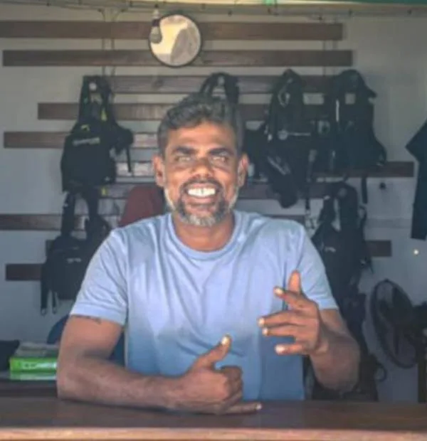 Un homme souriant est assis devant du matériel de plongée