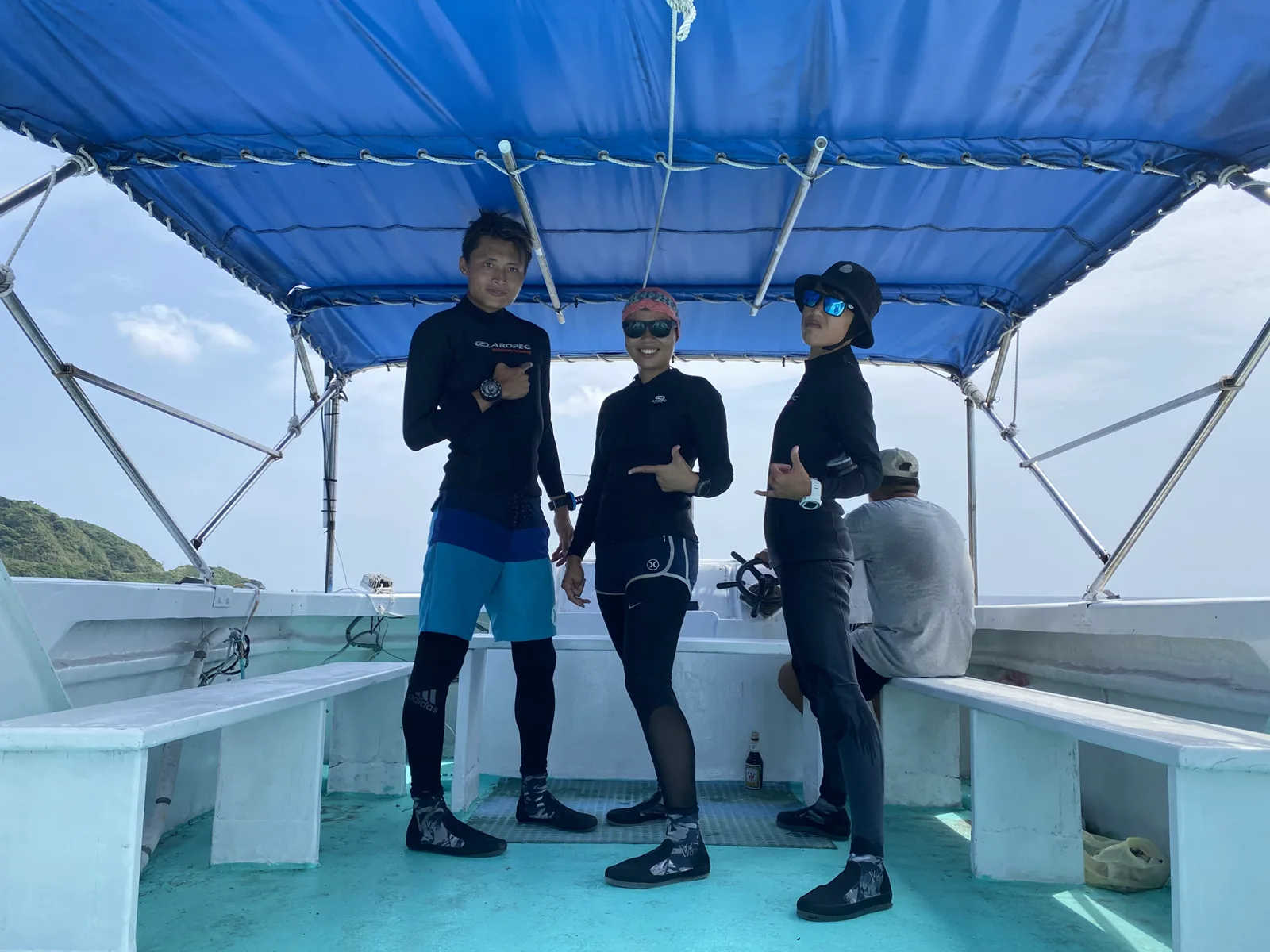 Trois plongeurs souriants posent sur le pont d'un bateau de plongée