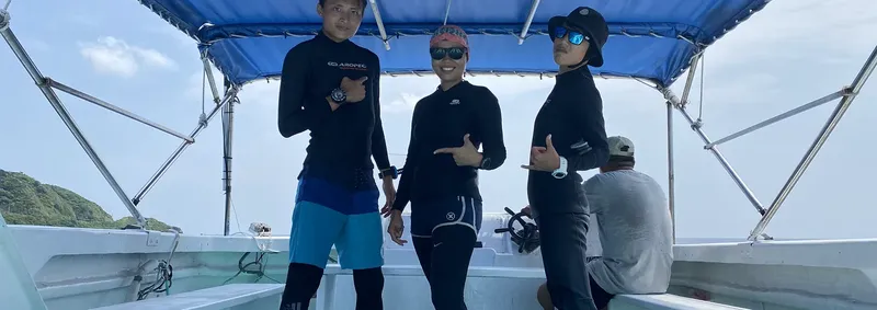Quatre personnes souriantes à bord d'un bateau de plongée en mer