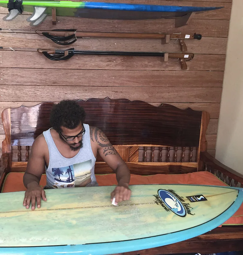 Un homme répare une planche de surf dans un atelier intérieur