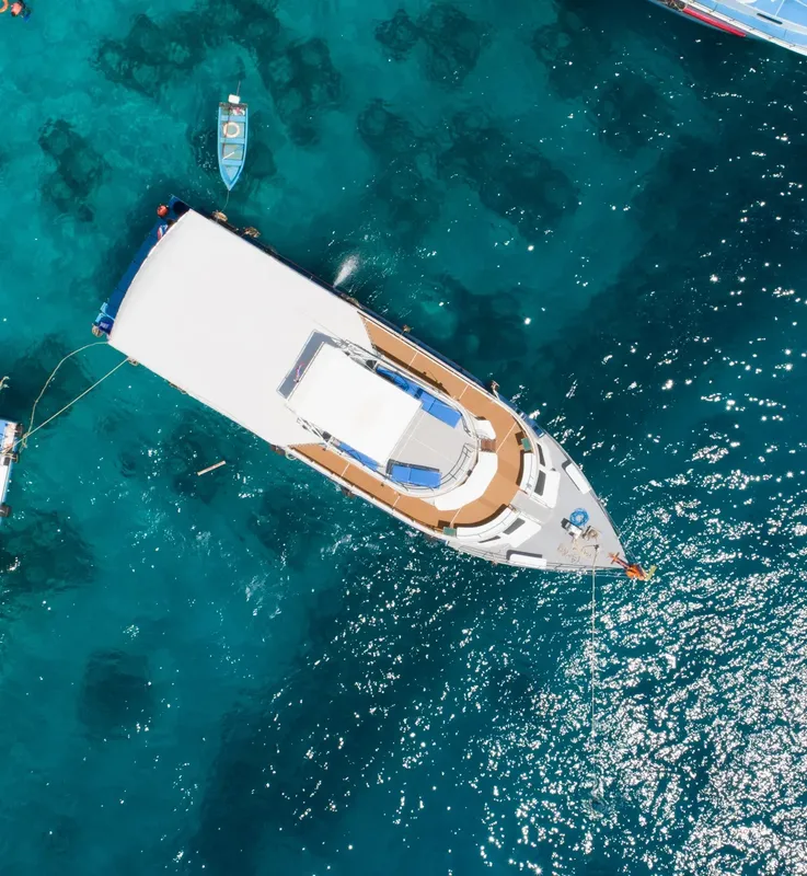 Vue aérienne d'un bateau de plongée amarré dans une eau turquoise claire