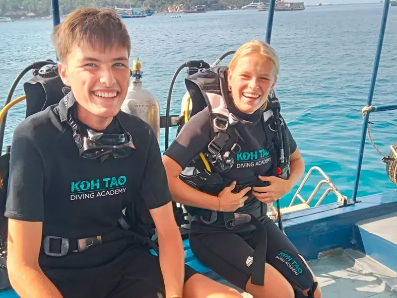 Deux plongeurs souriants sur un bateau avec leur équipement complet