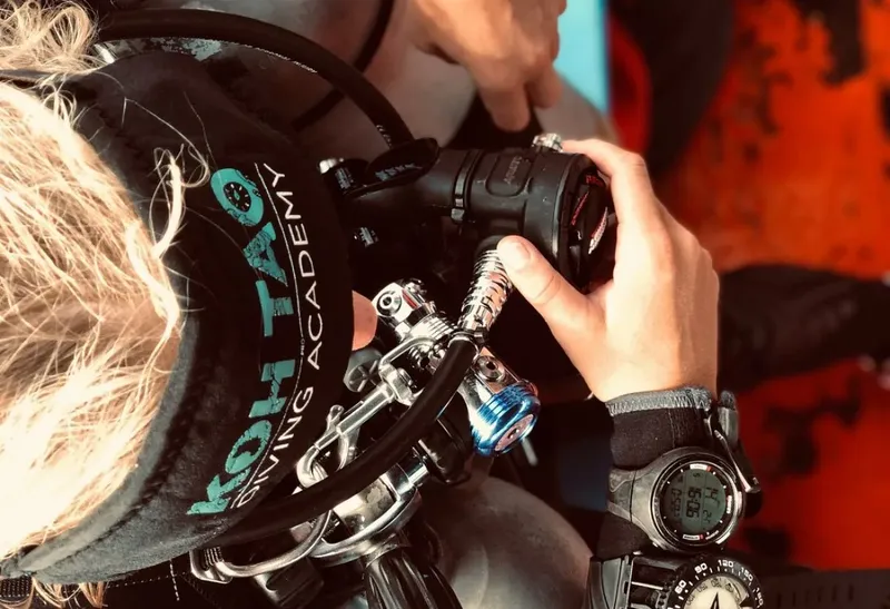 Plongeur manipule un appareil photo sous-marin avec un ordinateur de plongée