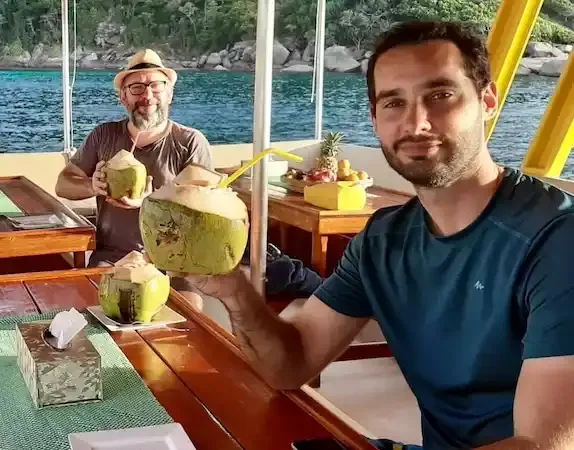 Deux hommes souriants sur un bateau avec des noix de coco