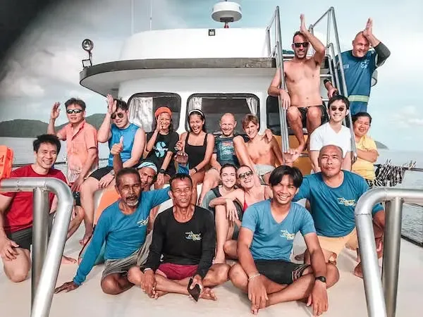 Groupe de personnes souriantes sur le pont d'un bateau de plongée