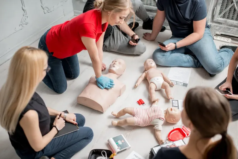 Groupe de personnes en formation aux premiers secours avec mannequins