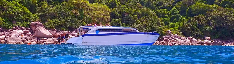 Bateau de plongée blanc et bleu amarré près d'une côte rocheuse