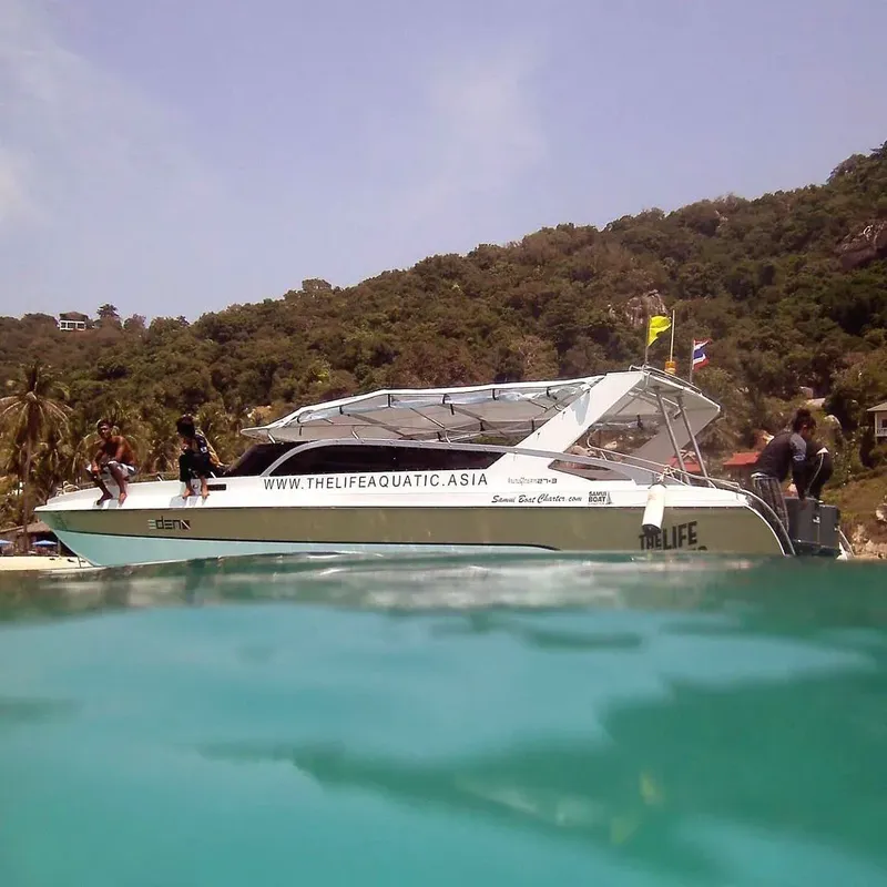 Bateau de plongée blanc et bleu navigue dans une eau turquoise claire