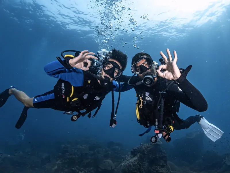 Deux plongeurs souriants font un signe OK sous l'eau