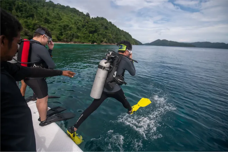 Plongeur s'apprête à entrer dans l'eau depuis un bateau pneumatique