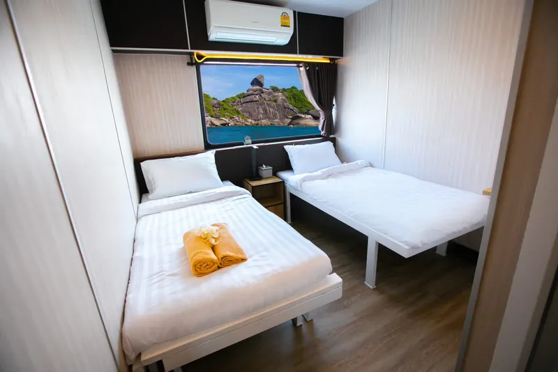 Intérieur de cabine de bateau avec deux lits et vue mer
