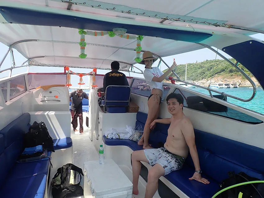 Personnes souriantes sur un bateau de plongée en direction d'une île