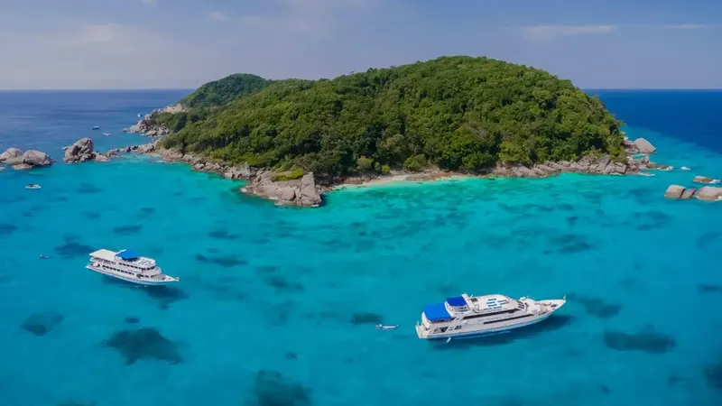 Île tropicale turquoise avec deux bateaux de plongée en mer