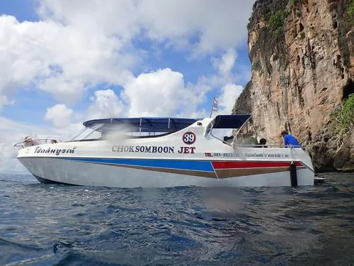 Bateau à moteur blanc et bleu navigue près d'une falaise rocheuse