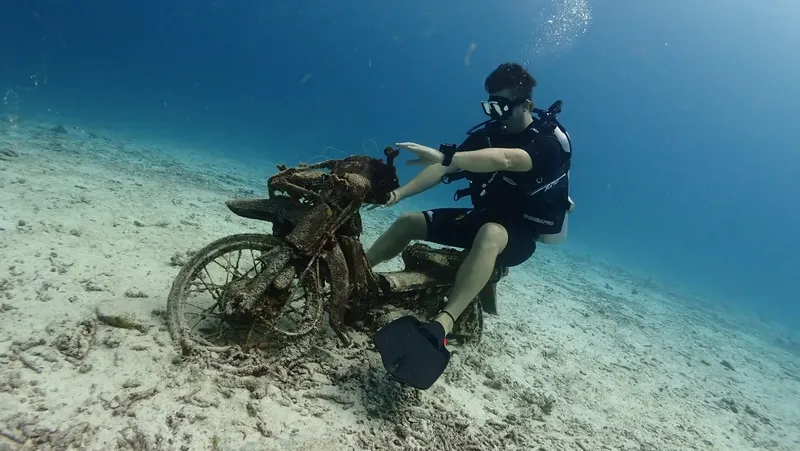 Plongeur assis sur une moto rouillée au fond de l'océan