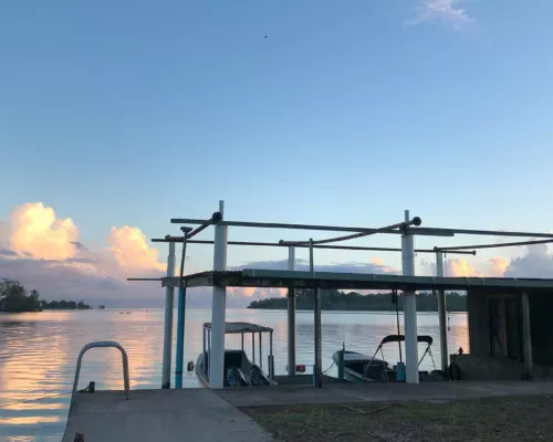 Quai avec bateaux amarrés sous une structure abritée au coucher du soleil