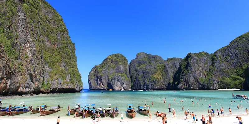 Plage paradisiaque avec des bateaux et des personnes se baignant
