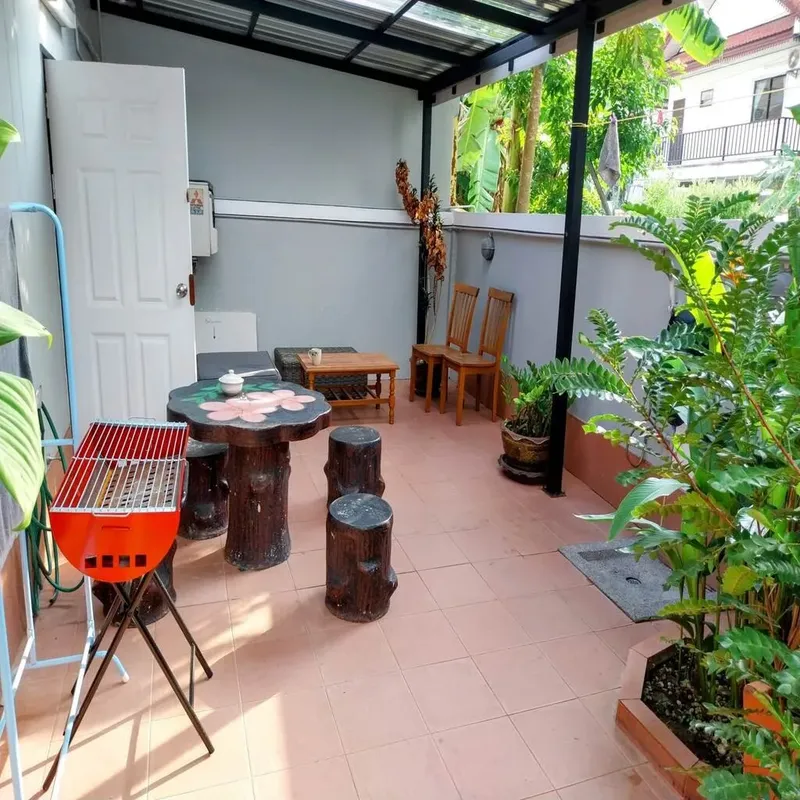 Espace extérieur aménagé avec mobilier de jardin et barbecue rouge