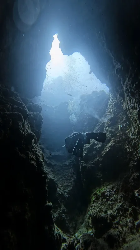 Plongeur explorant une grotte sous-marine avec une lumière descendante