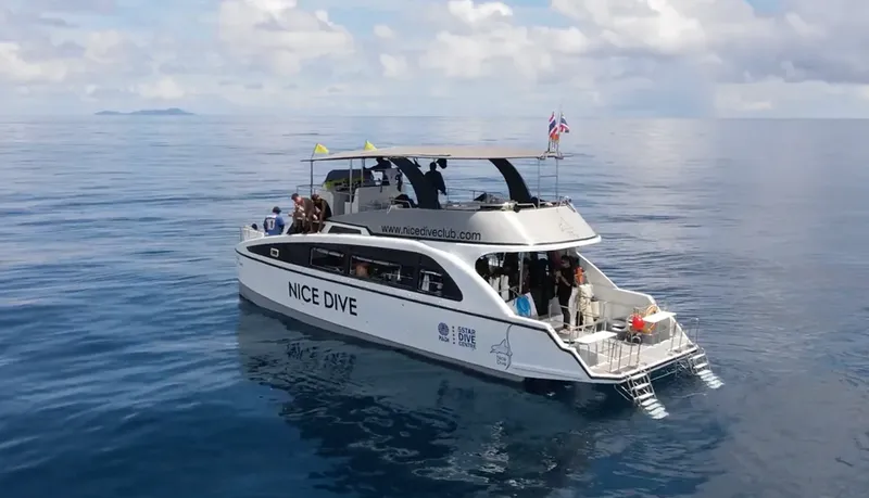 Catamaran blanc avec des plongeurs à bord en pleine mer