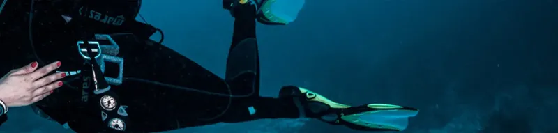 Plongeur en combinaison noire nageant dans une eau bleue profonde