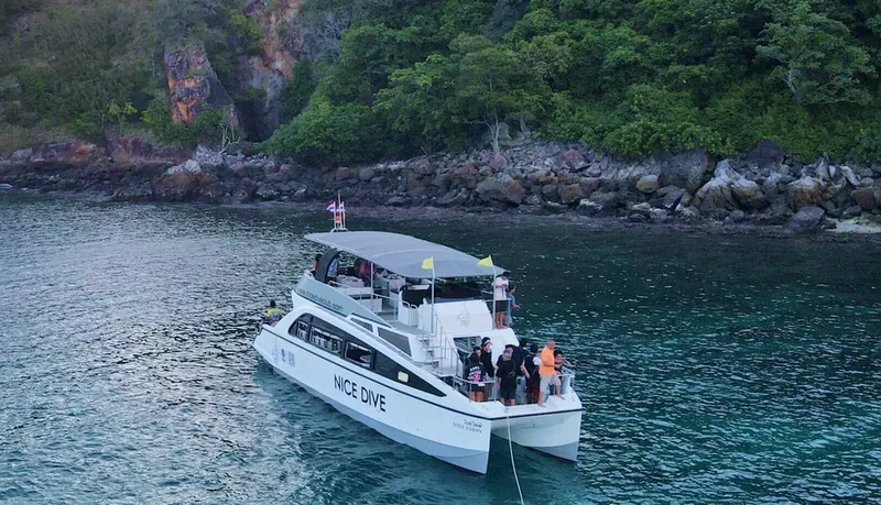 Catamaran de plongée avec des passagers en mer, paysage côtier
