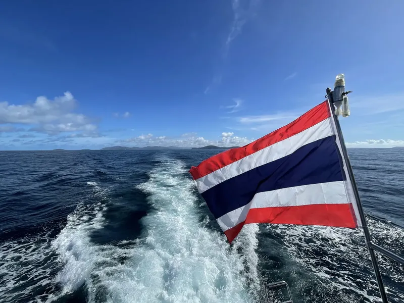 Drapeau thaïlandais flottant sur un bateau en pleine mer, ciel bleu