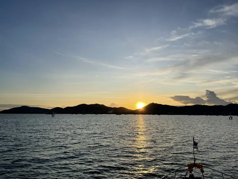 Coucher de soleil sur mer avec silhouette de montagnes et bateau