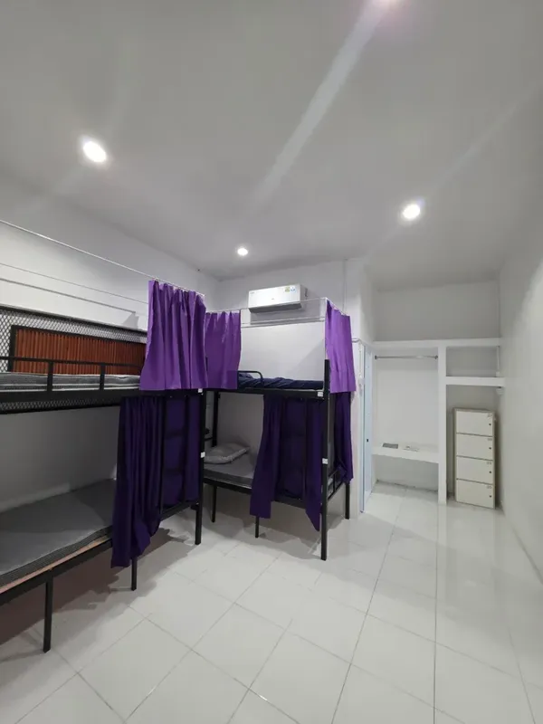 Lits superposés dans un dortoir avec rideaux violets et armoire blanche