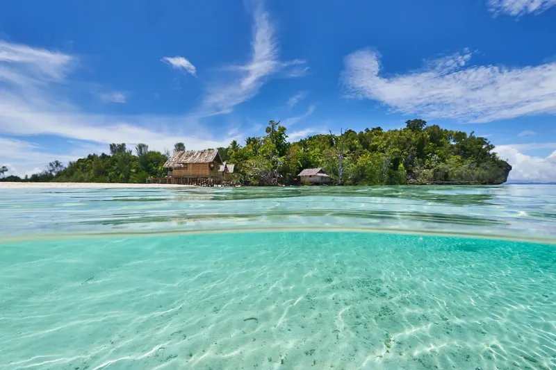 Île tropicale avec bâtiments sur pilotis et eau turquoise claire
