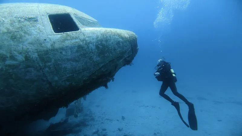 Plongeur explorant l'épave d'un avion sous l'eau bleu clair