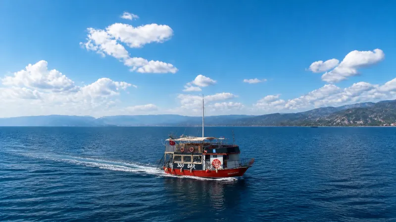 Bateau rouge naviguant sur une mer bleue sous un ciel nuageux