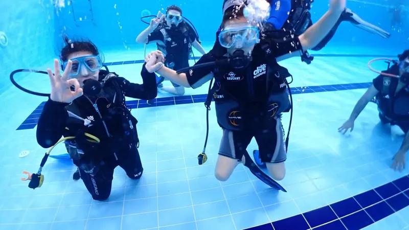 Plongeurs en formation dans une piscine, sourires et signes de validation
