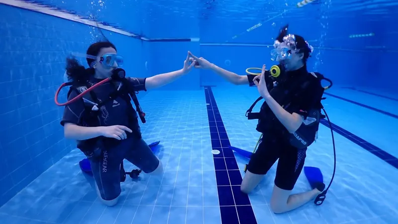Deux plongeurs s'accordent la main dans une piscine, équipement complet