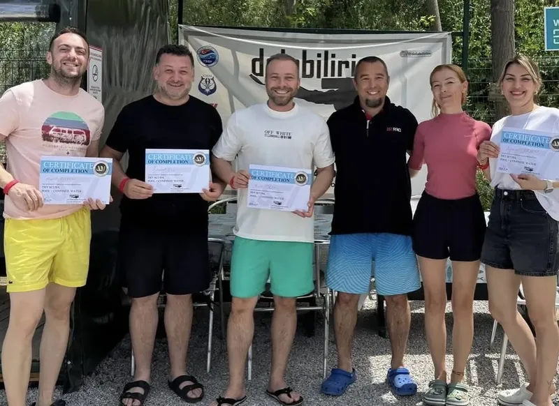 Groupe de plongeurs souriants tenant des certificats de formation en plongée