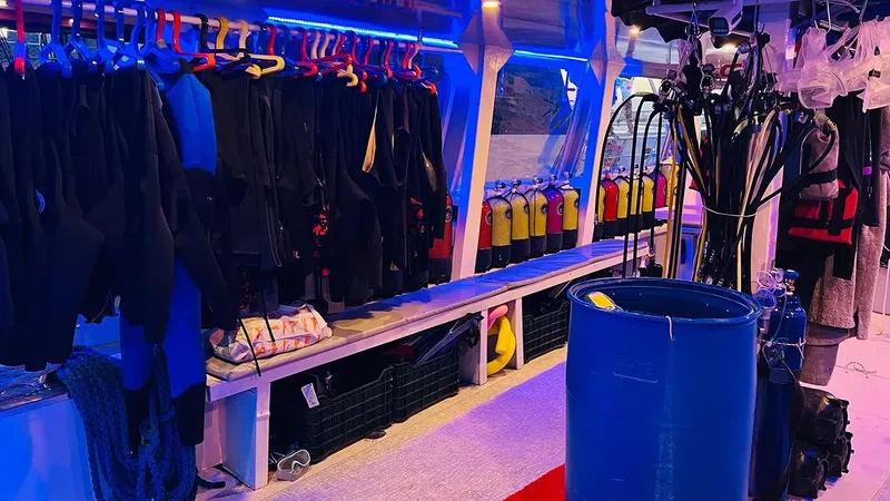 Combinaisons de plongée, bouteilles et matériel rangés dans un local intérieur