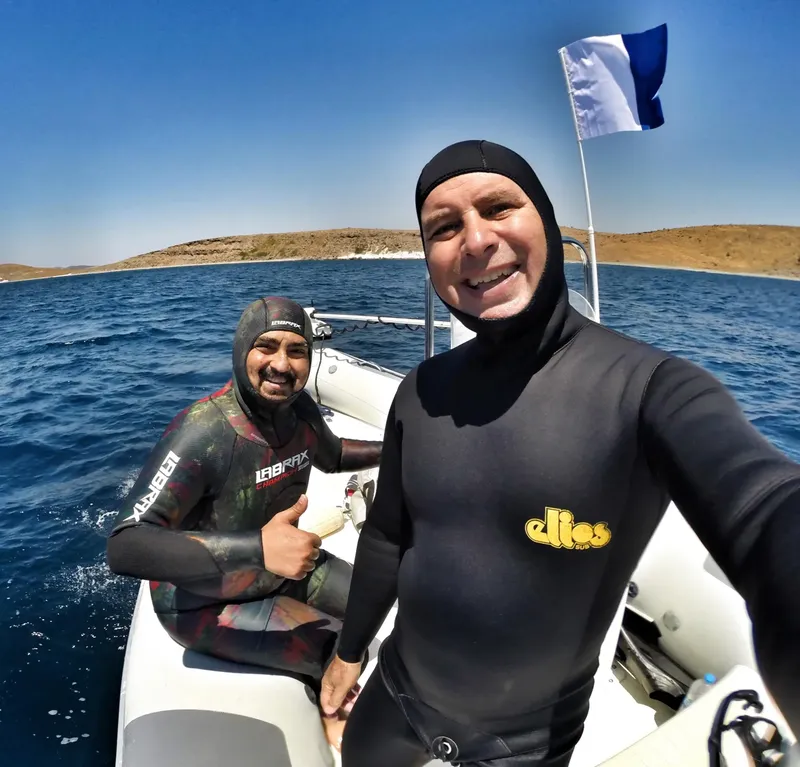 Deux plongeurs souriants en combinaison sur un bateau en mer