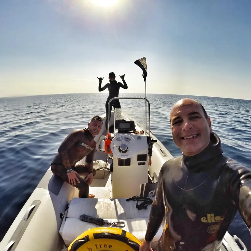 Trois personnes souriantes à bord d'un bateau pneumatique en mer