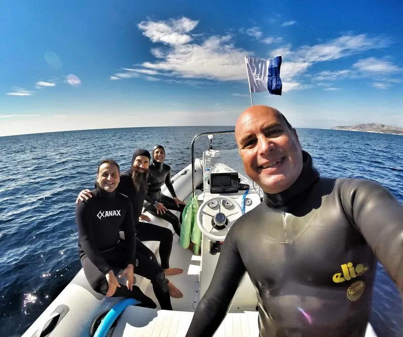Quatre personnes en combinaison de plongée sur un bateau pneumatique en mer