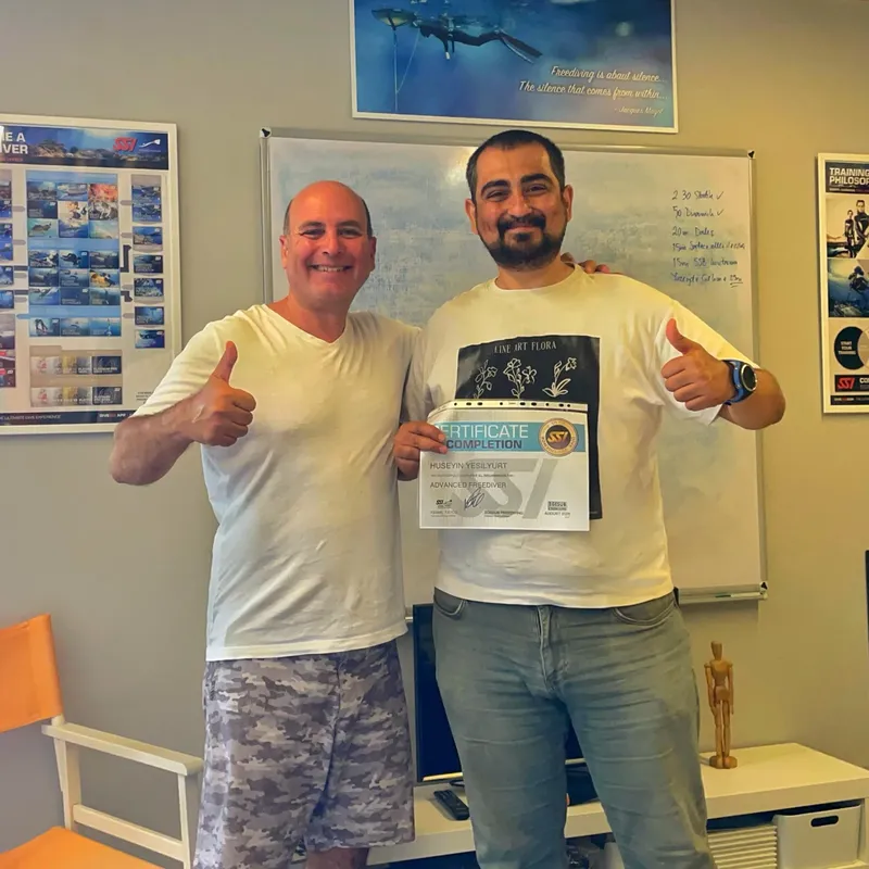 Deux hommes souriants montrent un certificat de formation plongée