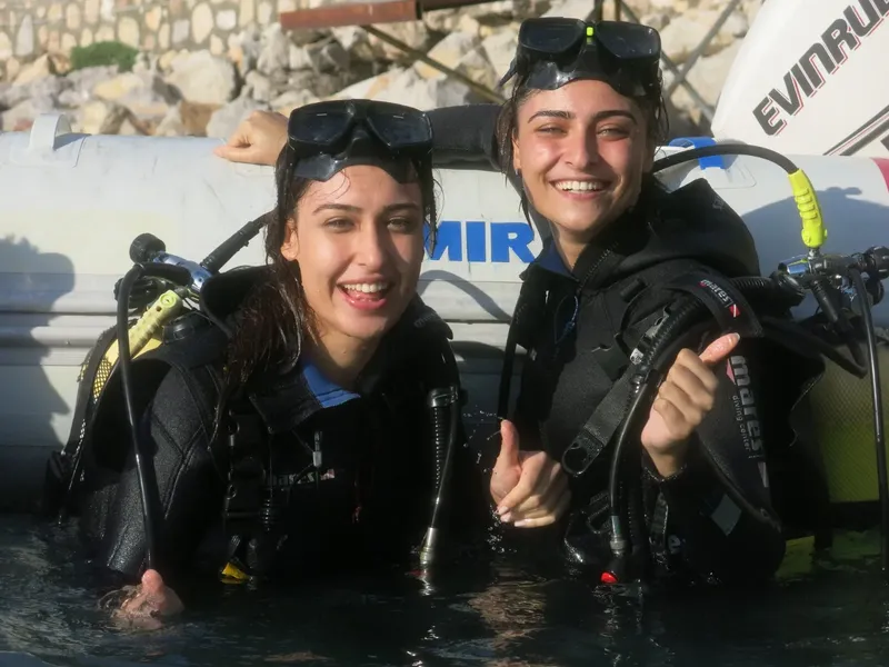 Deux plongeuses souriantes avec leur équipement sur un bateau