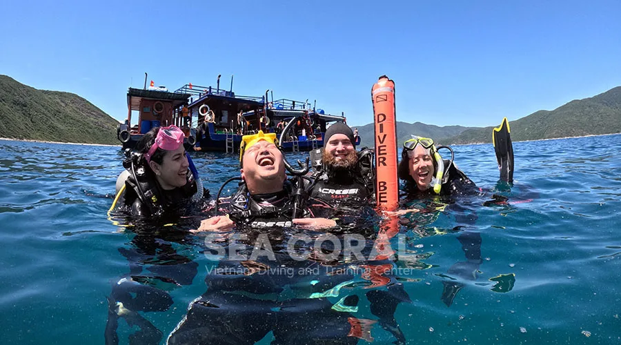 Plongeurs souriants en surface près d'un bateau de plongée bleu