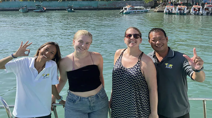 Quatre personnes souriantes posent sur un bateau en mer