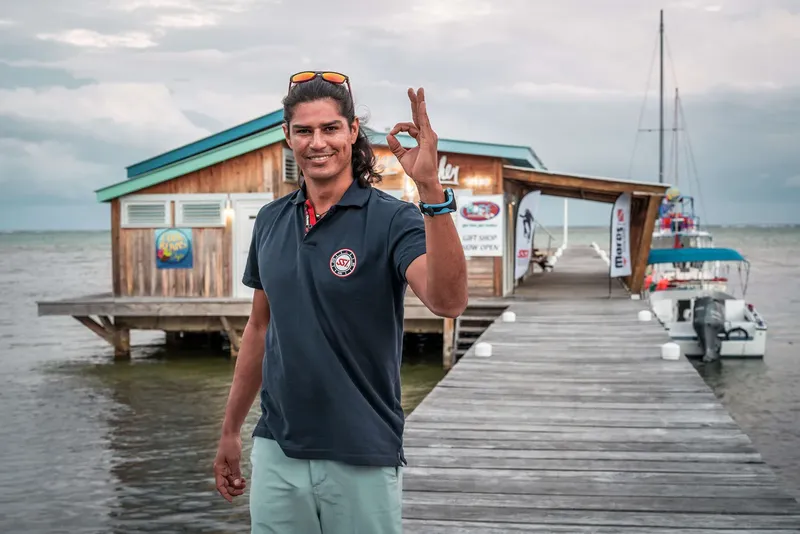Un homme souriant fait un signe OK sur un ponton en bois