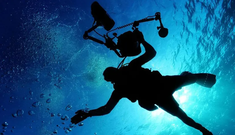 Plongeur en silhouette nageant vers le soleil dans l'eau bleue